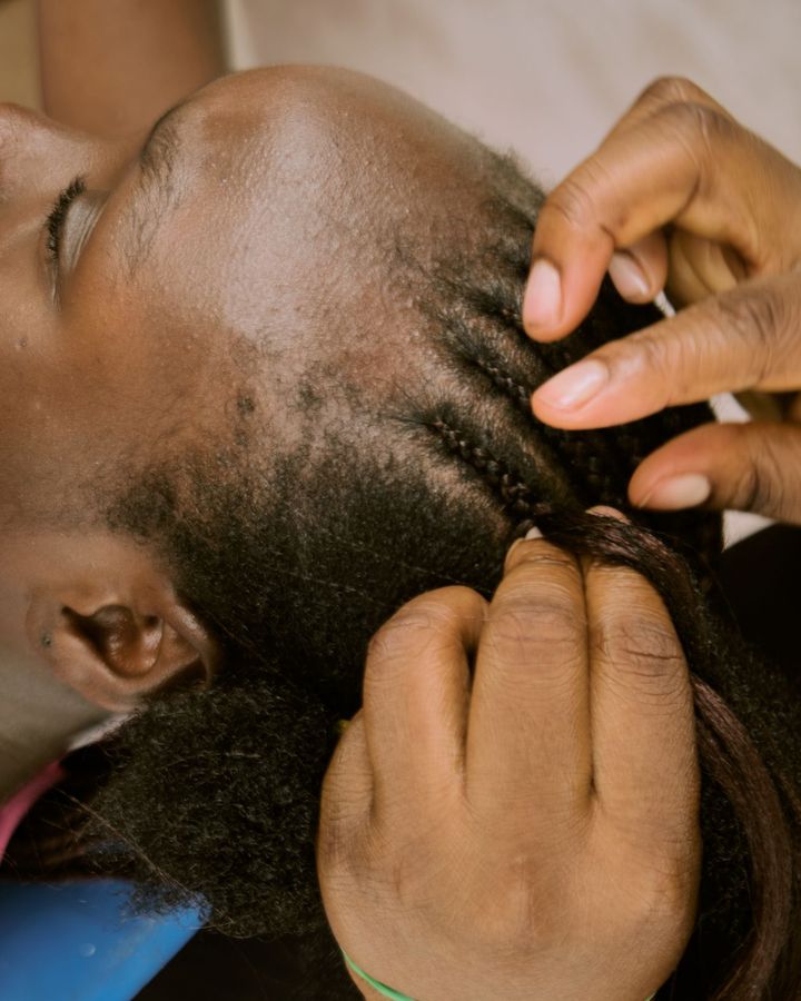 Hands braiding hair close to the scalp