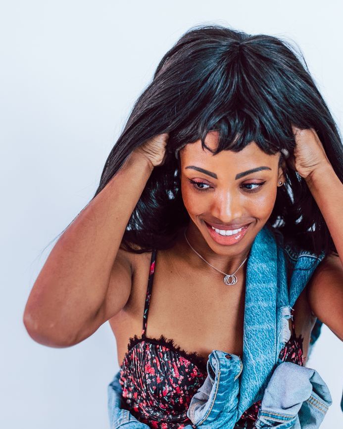 Woman smiling while fitting a dark wig